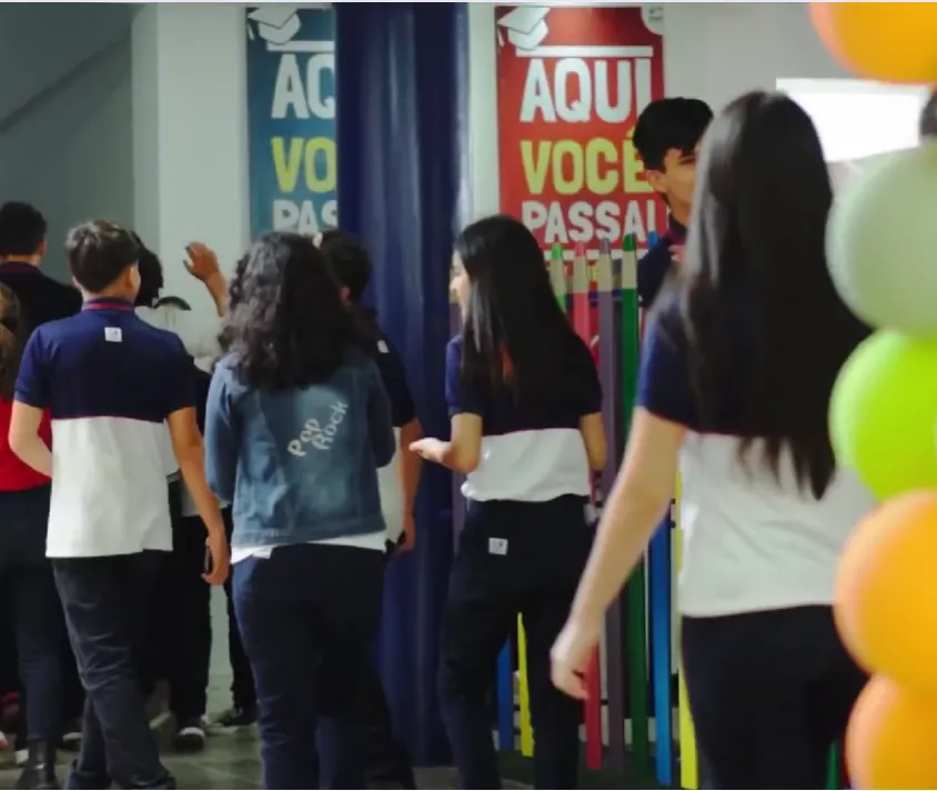 Estudantes do Colégio Maria Stela caminhando juntos em um espaço decorado da escola
